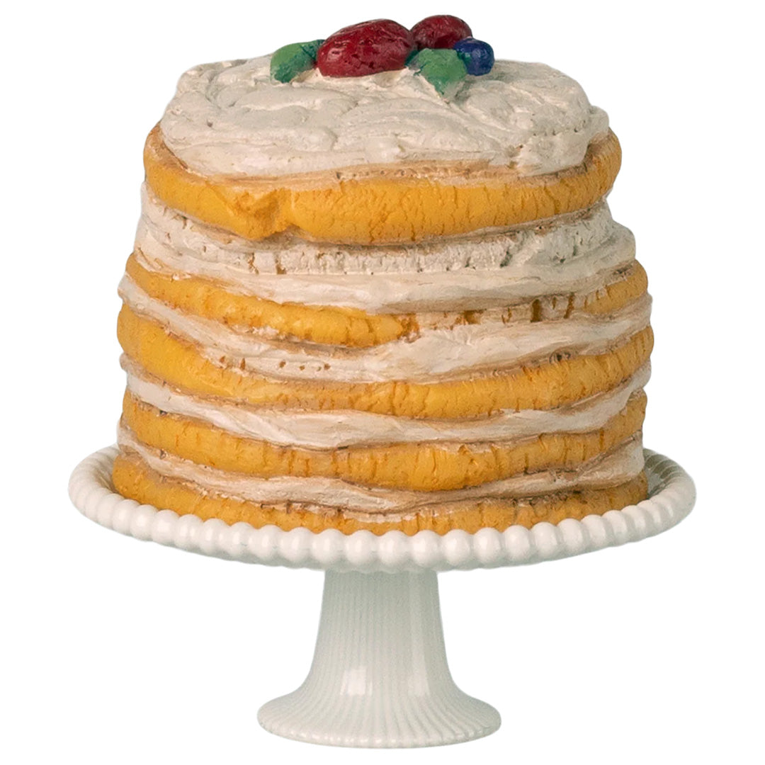 Maileg poppenhuis taart met witte frosting en bessen op een wit plateau.