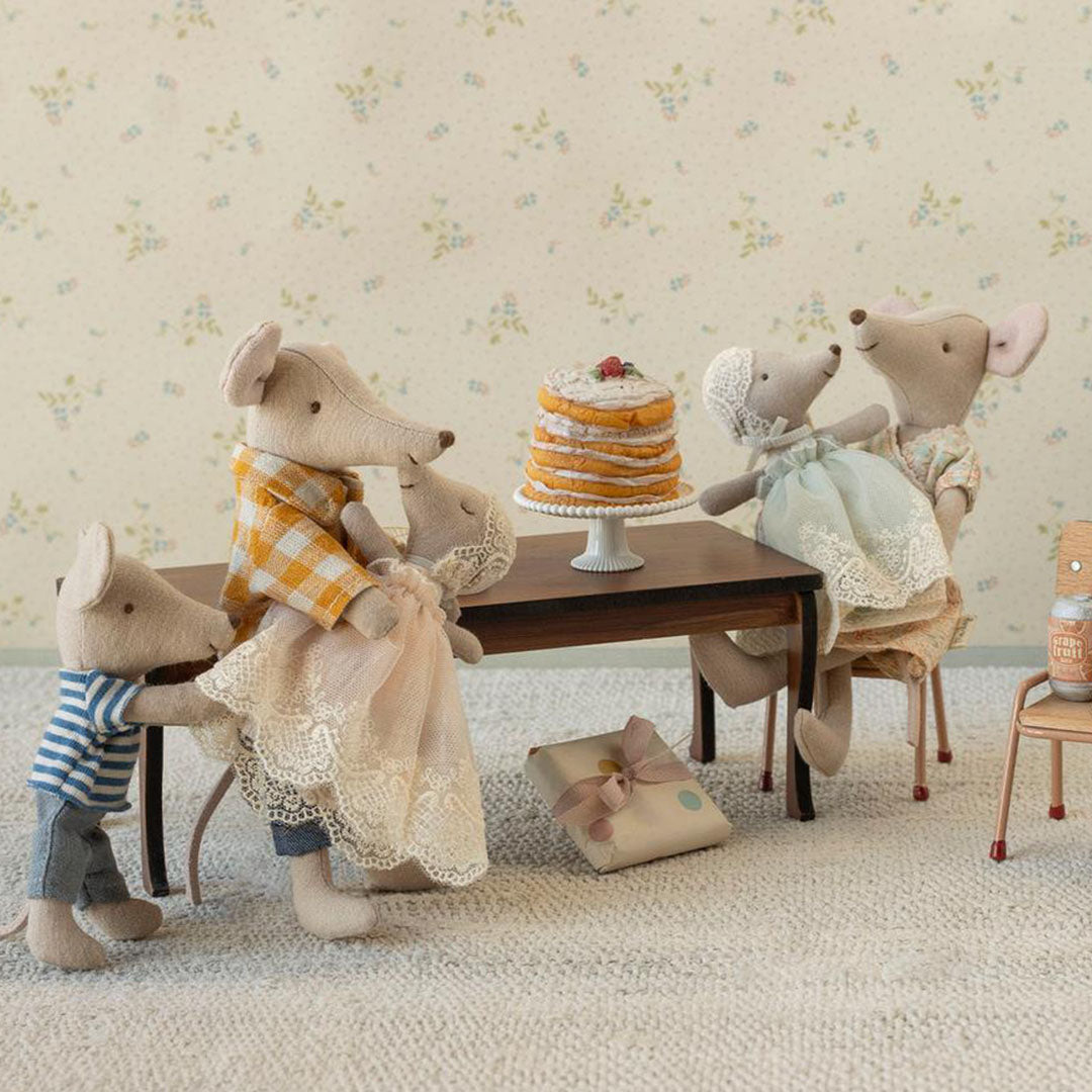 Maileg muizenfamilie zit aan een tafel met de poppenhuis taart en een cadeau.