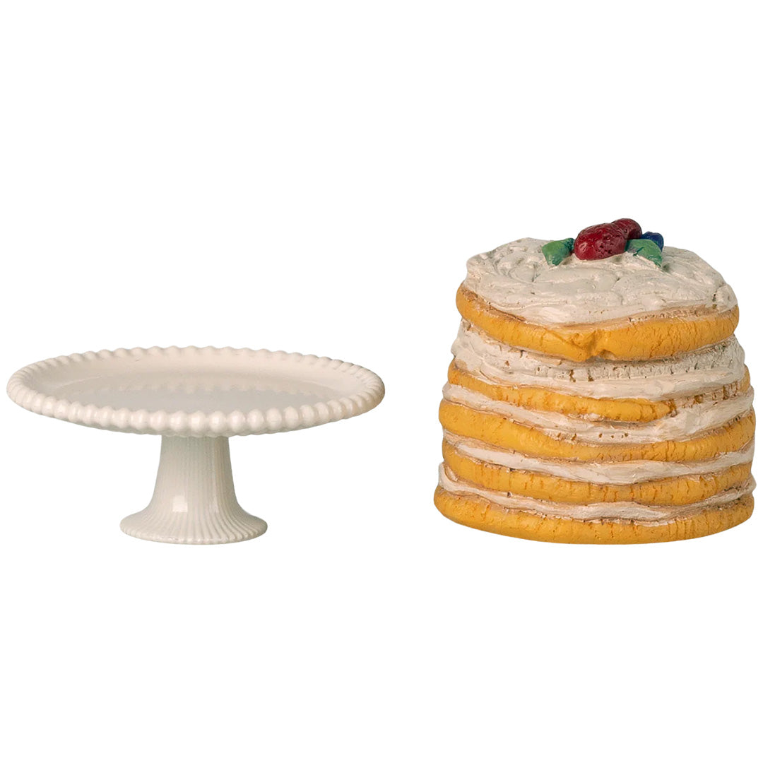 Maileg poppenhuis taart met witte frosting en bessen naast het losse witte plateau.
