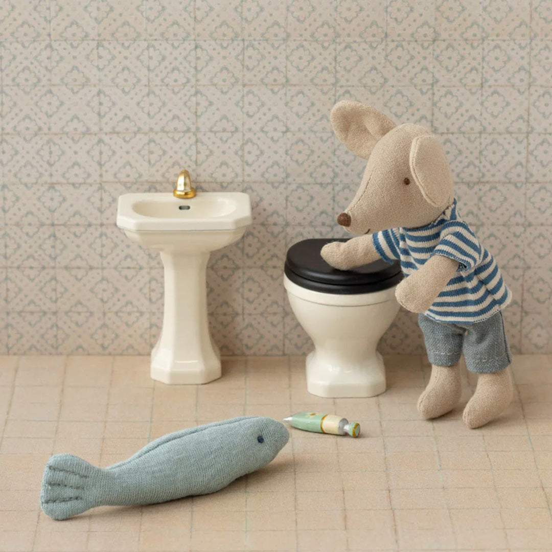 Maileg muis in een poppenhuis badkamer met wastafel, toilet en een stoffen vis op de vloer.