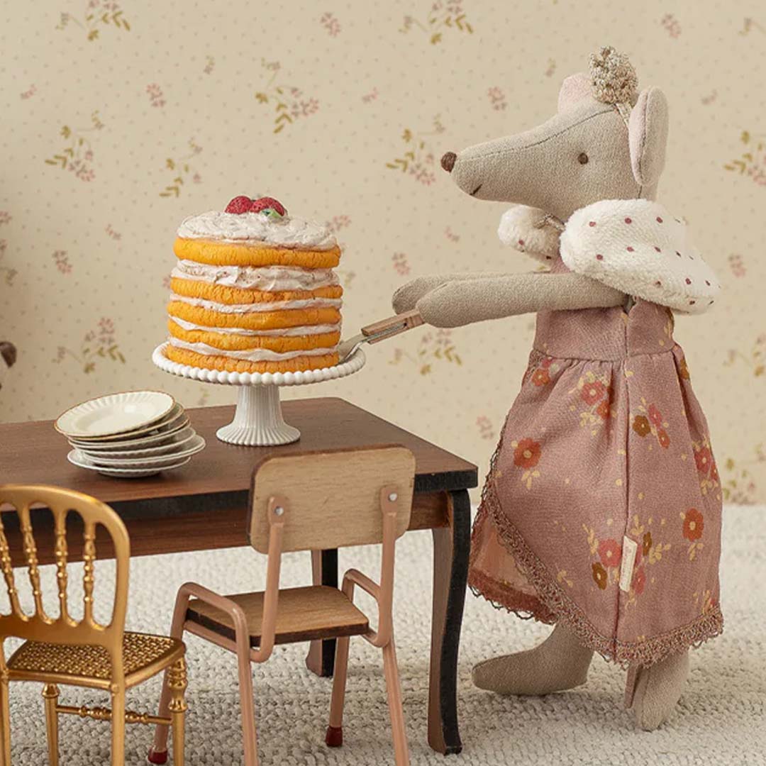 Maileg muispop in koninginnenjurk en kroon serveert taart aan een miniatuurtafel.
