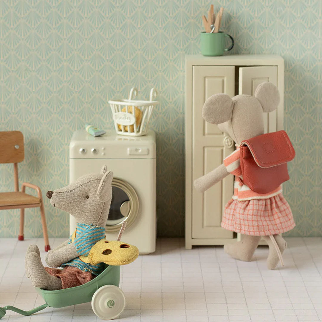 Maileg grote zus muis pop met gestreept topje, geruite rok en bruine tas in een speelkamer.