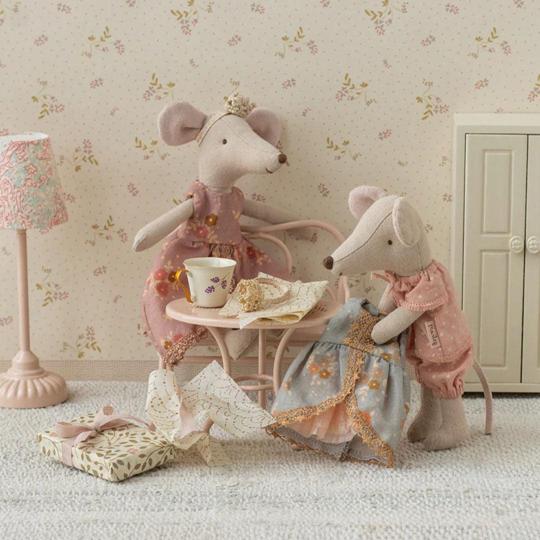 Twee Maileg muizen in een miniatuurkamer, één houdt de prinsessenjurk vast en de ander zit aan een tafeltje.