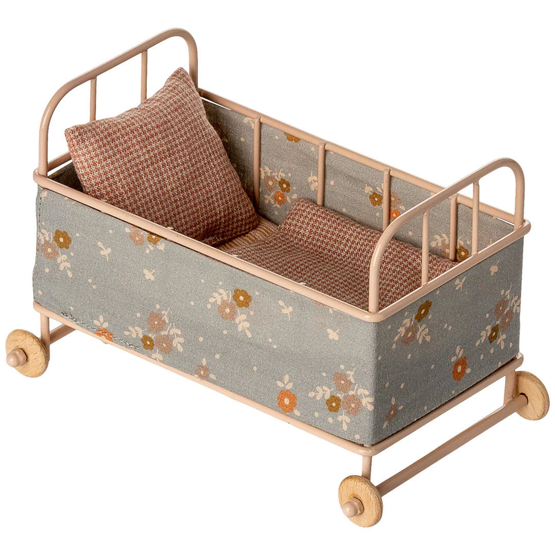 Maileg poppenreisbed met roze metalen frame, houten wielen en een grijsblauw bloemenpatroon, inclusief kussen en deken.