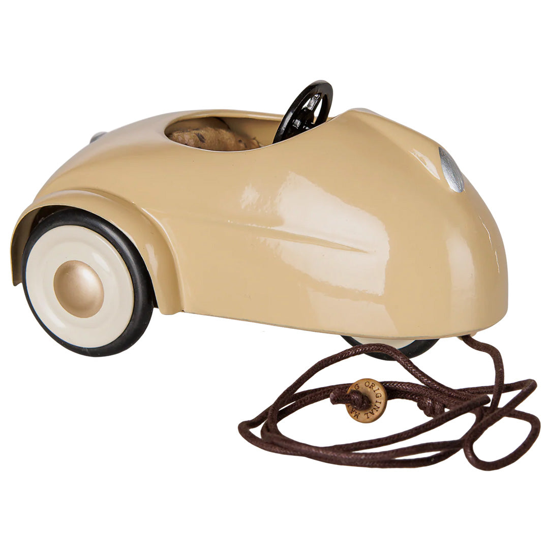 Maileg beige speelauto met trekkoord, schuin van voren gefotografeerd.