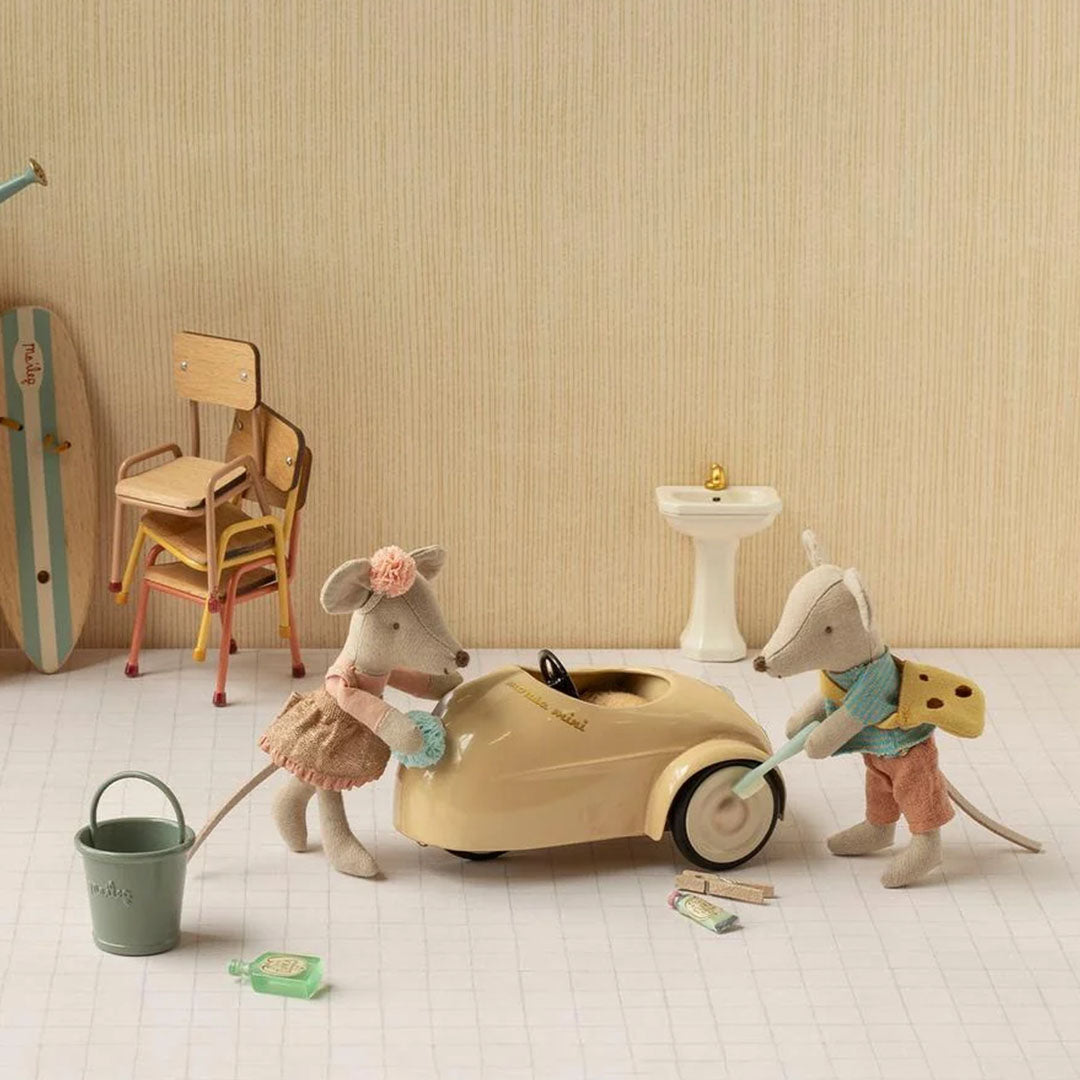 Twee Maileg muizenpoppen wassen de beige speelauto met een emmer en zeep in een speelsetting.