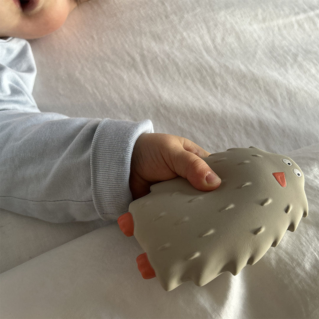 Een babyhandje houdt het Maison Petit Jour bijtspeelgoed in de vorm van een beige yeti vast.