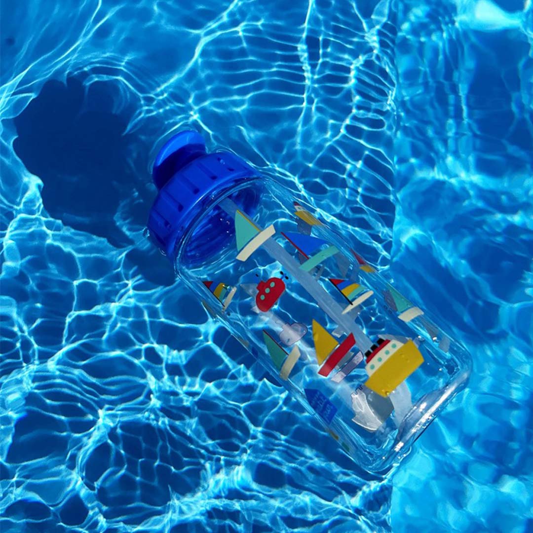 De drinkfles met botenpatroon drijft in een zwembad met blauw water.