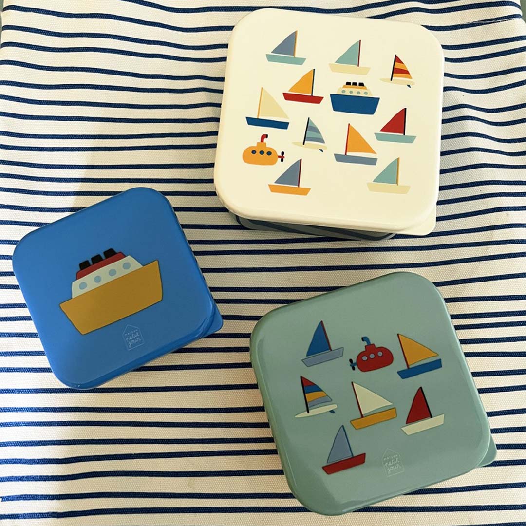 Drie maison petit jour snackdoosjes met botenpatroon op een blauw-wit gestreepte ondergrond.