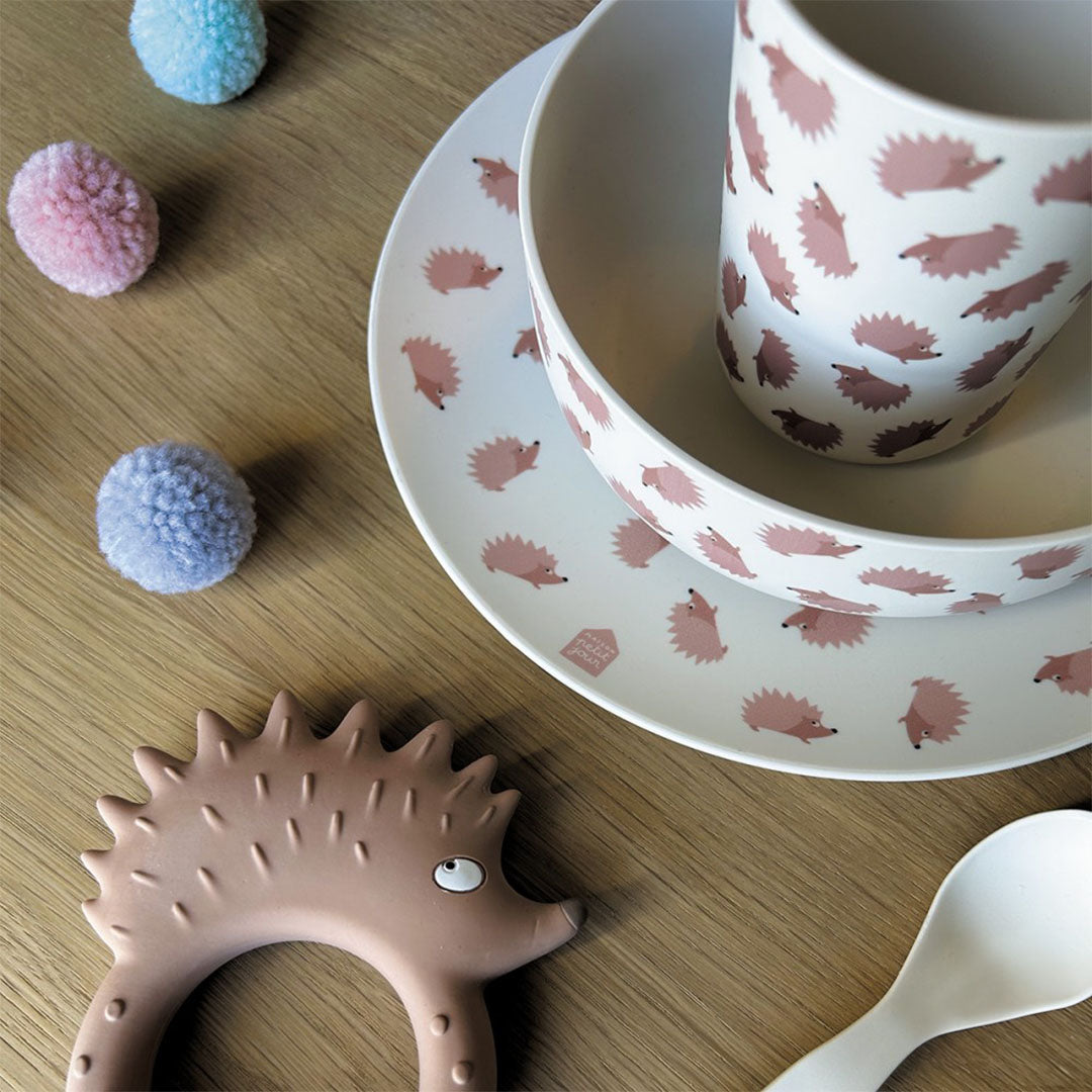 Maison petit jour babyservies met egelpatroon, samen met een egel bijtring en pom-poms op een houten ondergrond.