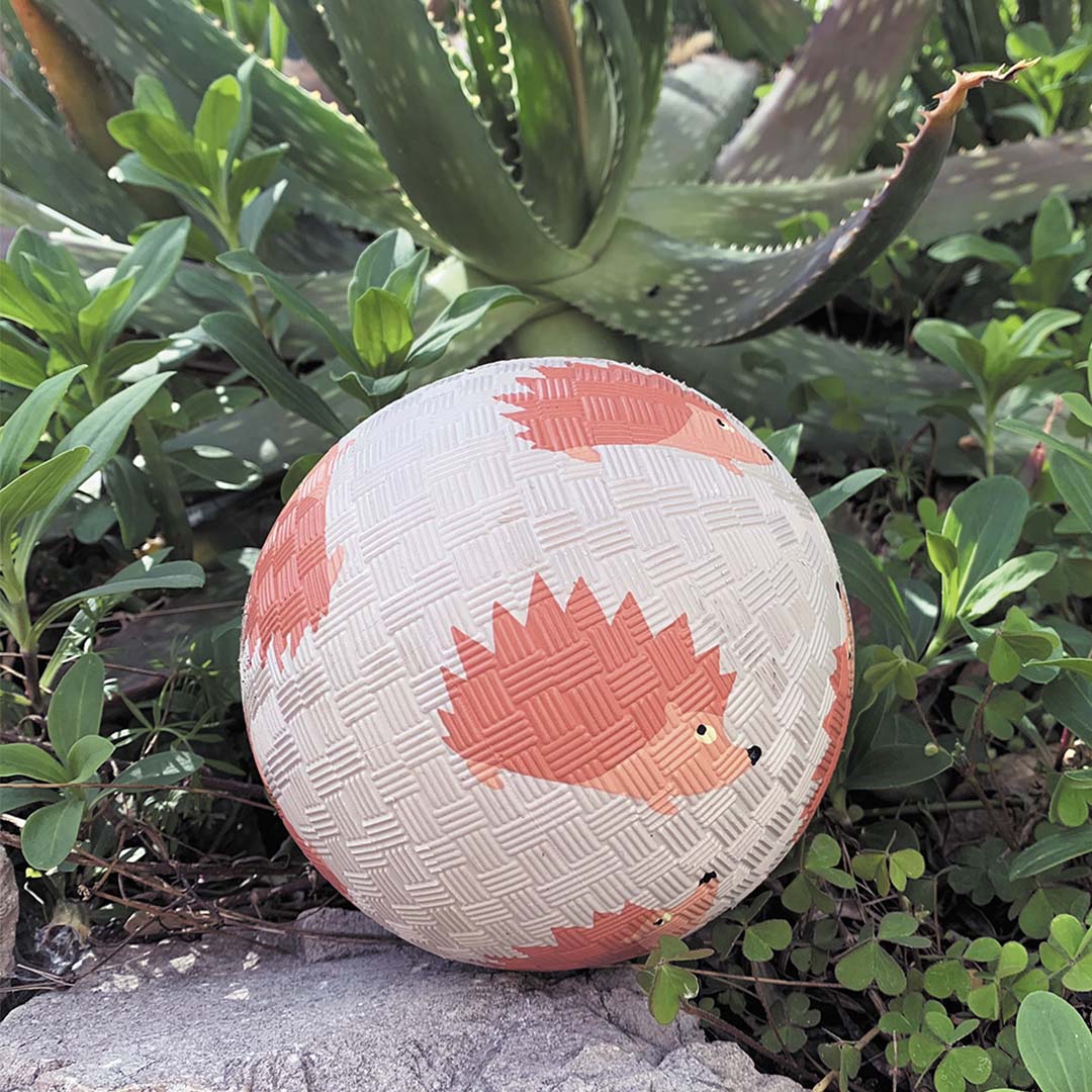 Een maison petit jour speelbal met egelpatroon ligt op een steen in de tuin.