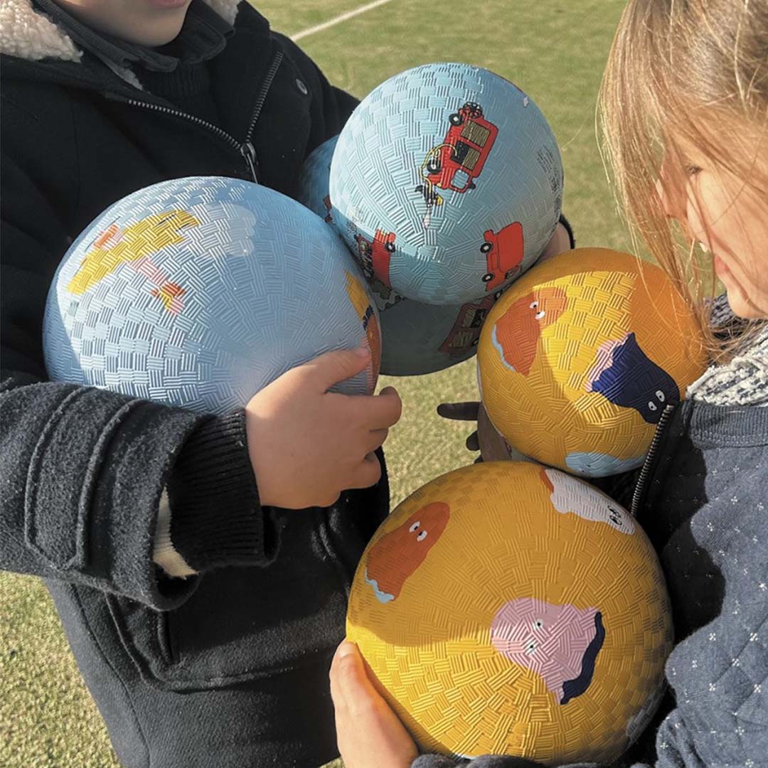 Twee kinderen houden vier speelballen vast, waaronder blauwe ballen met luchtvoertuigen en gele ballen met dieren.
