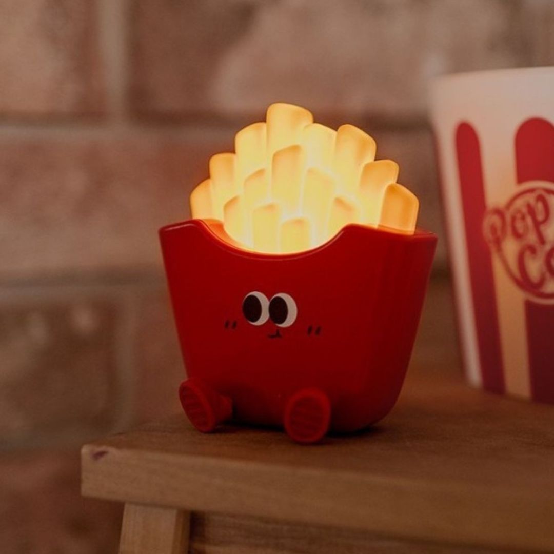 mary's friet nachtlampje dat warm geel licht geeft, staand op een houten plank.