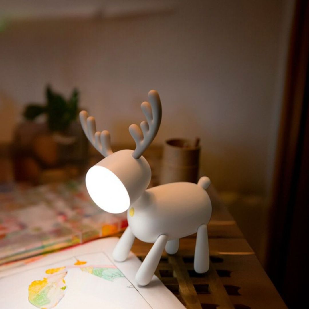 Het Mary's witte hert nachtlampje staat op een tafel en verlicht een tekening.
