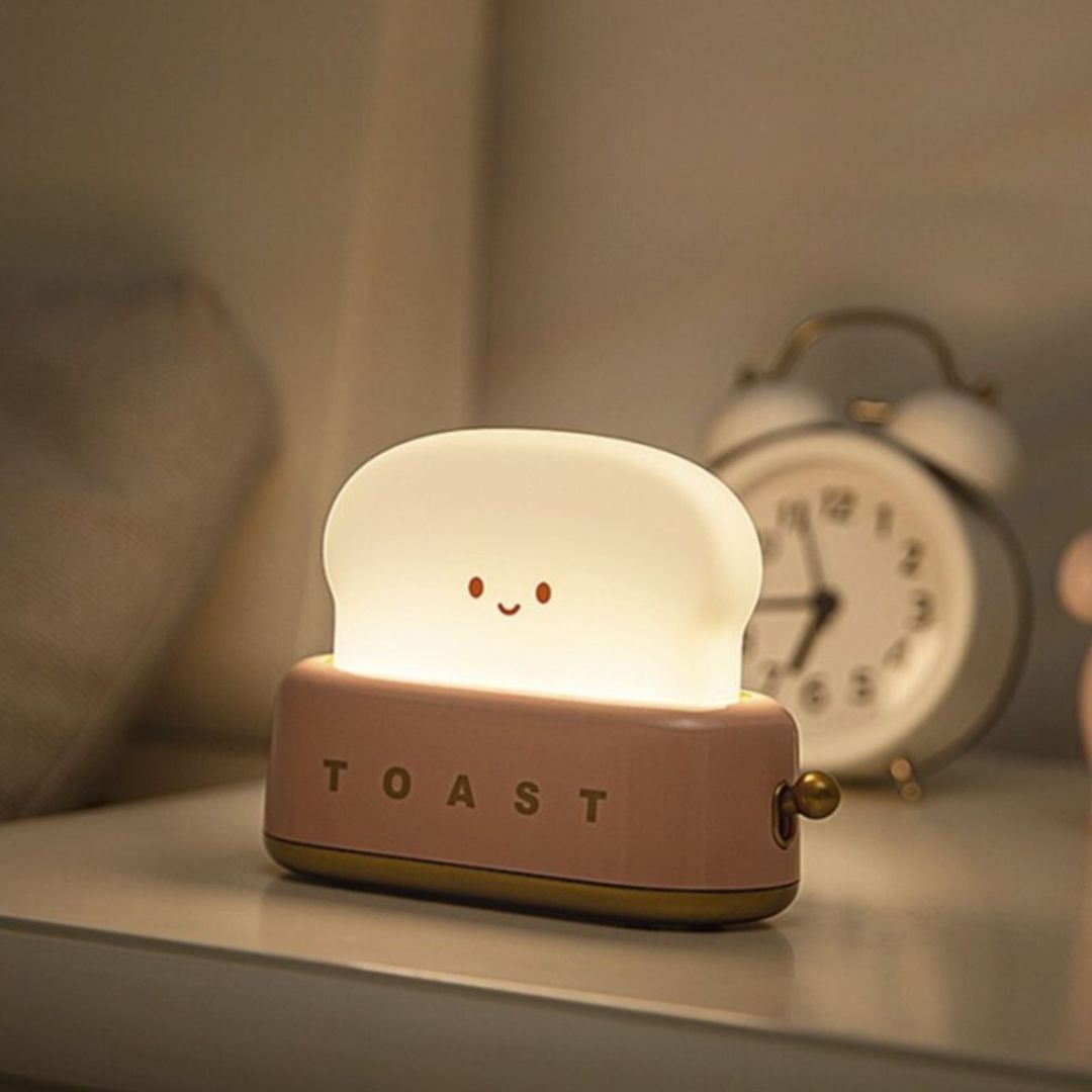 Mary's roze toaster nachtlampje dat warm wit licht geeft op een nachtkastje.