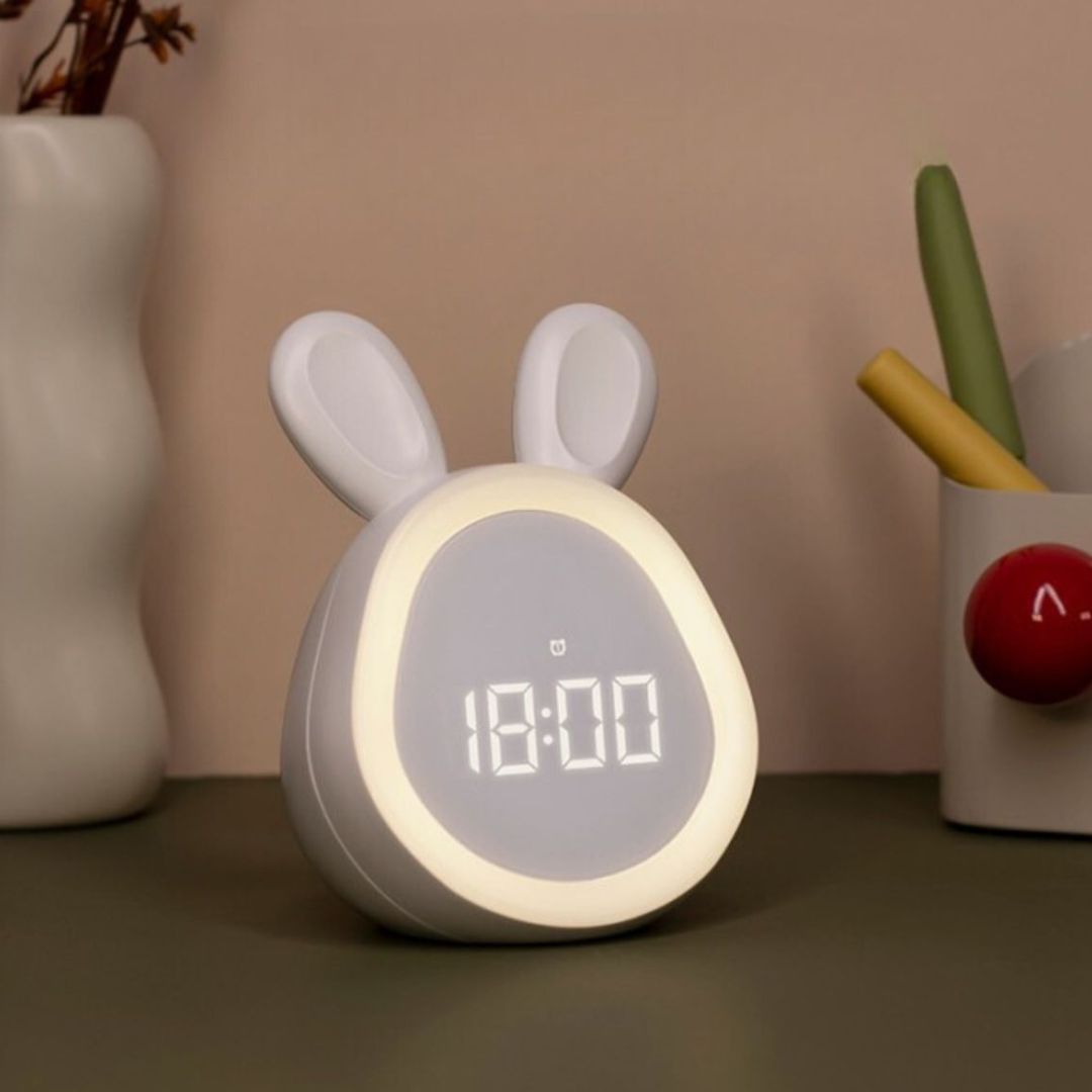 Wit konijn wekker en nachtlampje met digitale tijd '18:00' op een bureau.