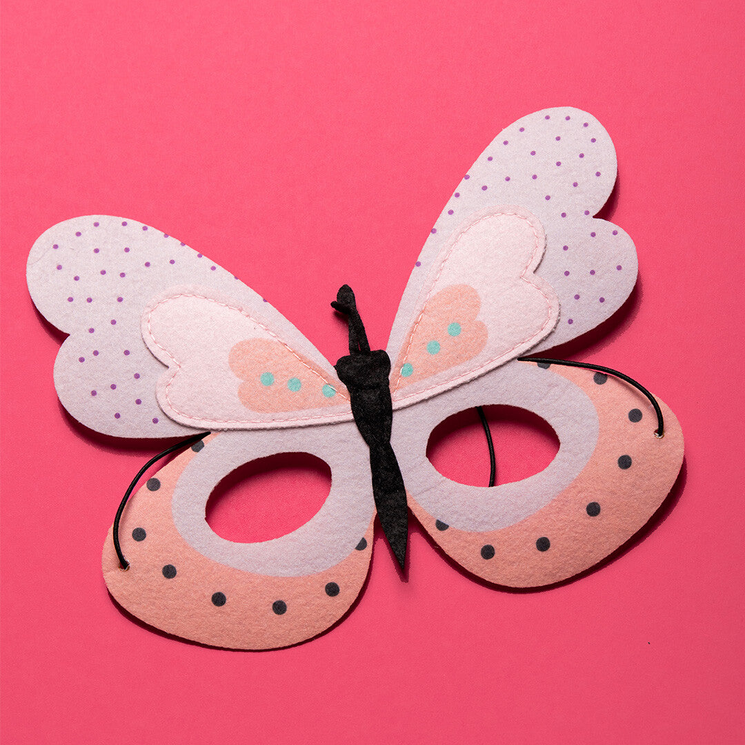 Folat vilten vlindermasker met elastiek, liggend op een roze ondergrond.