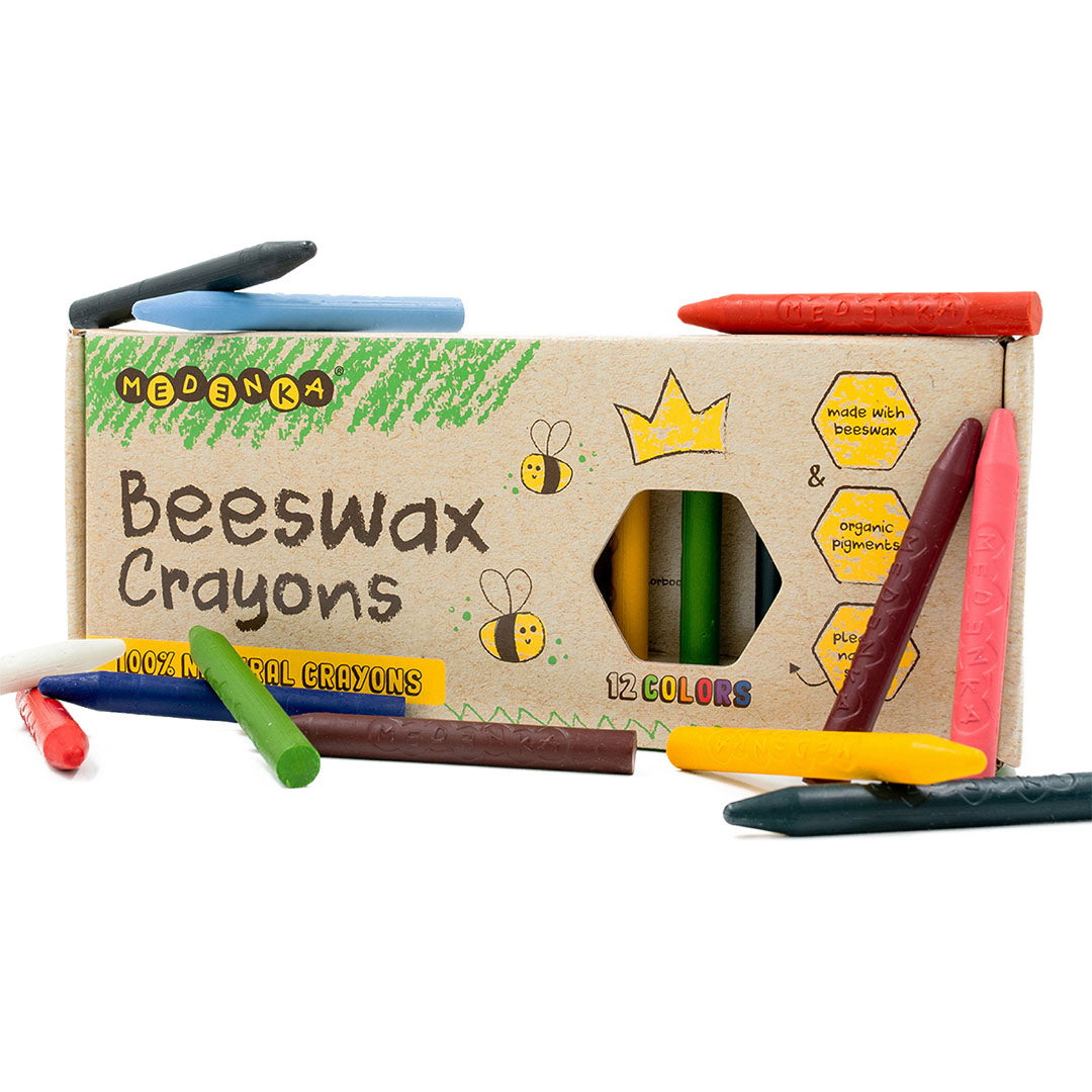 Medenka bijenwaskrijtjes in een open kartonnen doos met bijenillustraties en enkele losse krijtjes.
