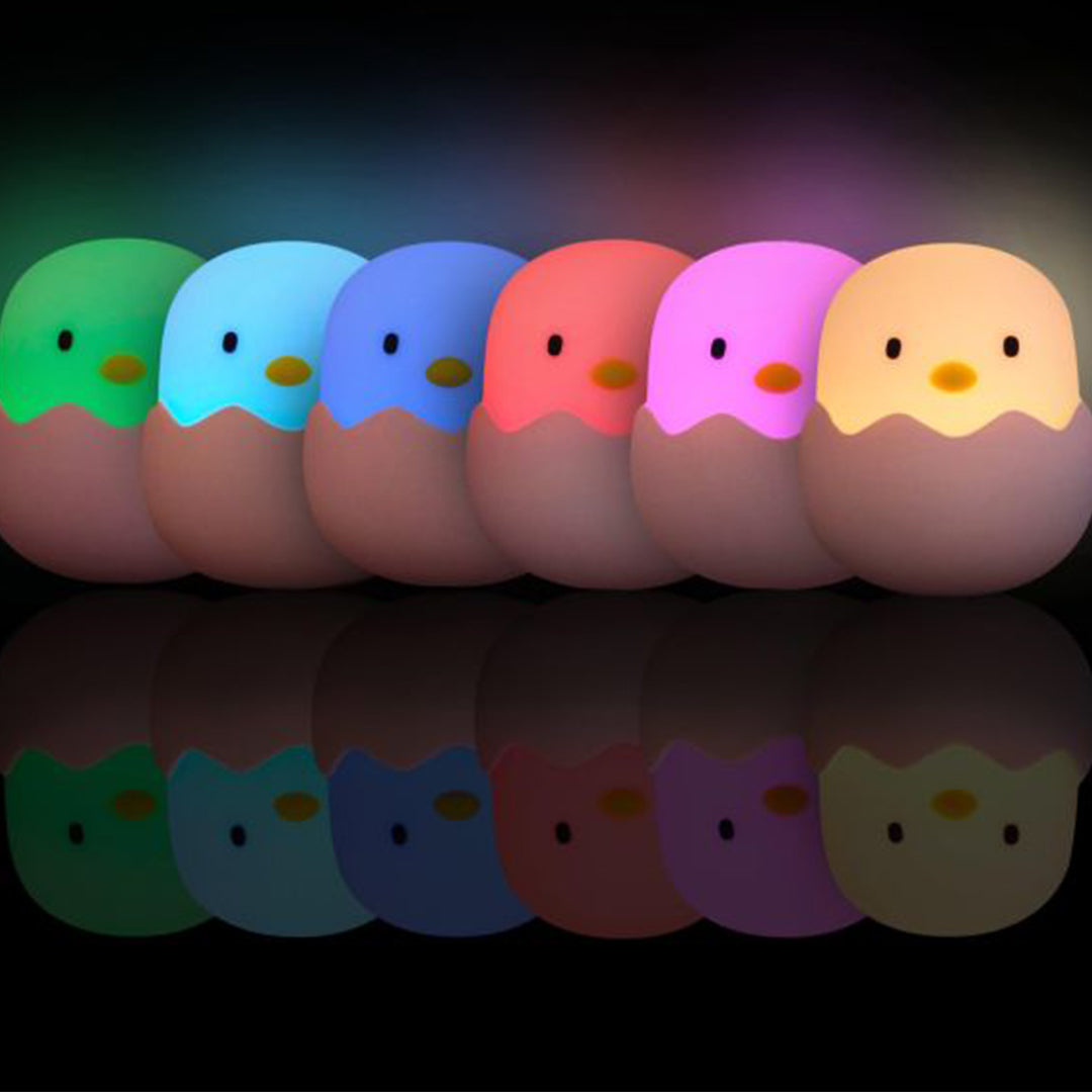 Zeven megalight kuiken nachtlampjes in verschillende kleuren, op een rij met reflectie.