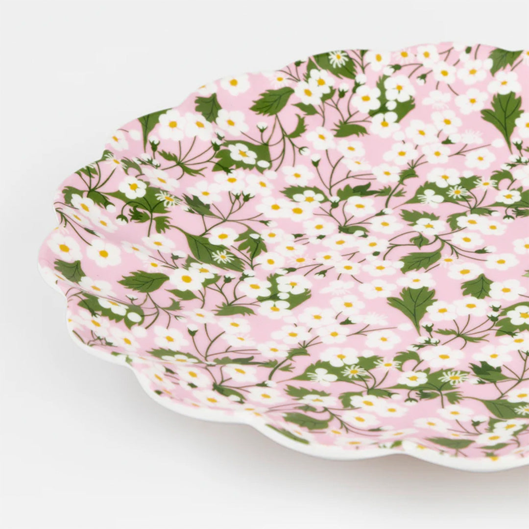Detail van een roze Meri Meri melamine bord met witte bloemen en een geschulpte rand.