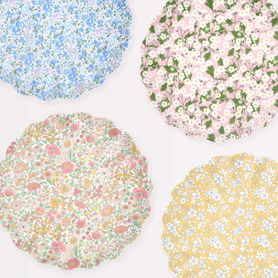 Vier Meri Meri melamine borden met verschillende gebloemde patronen in roze, geel, blauw en roze-geel.