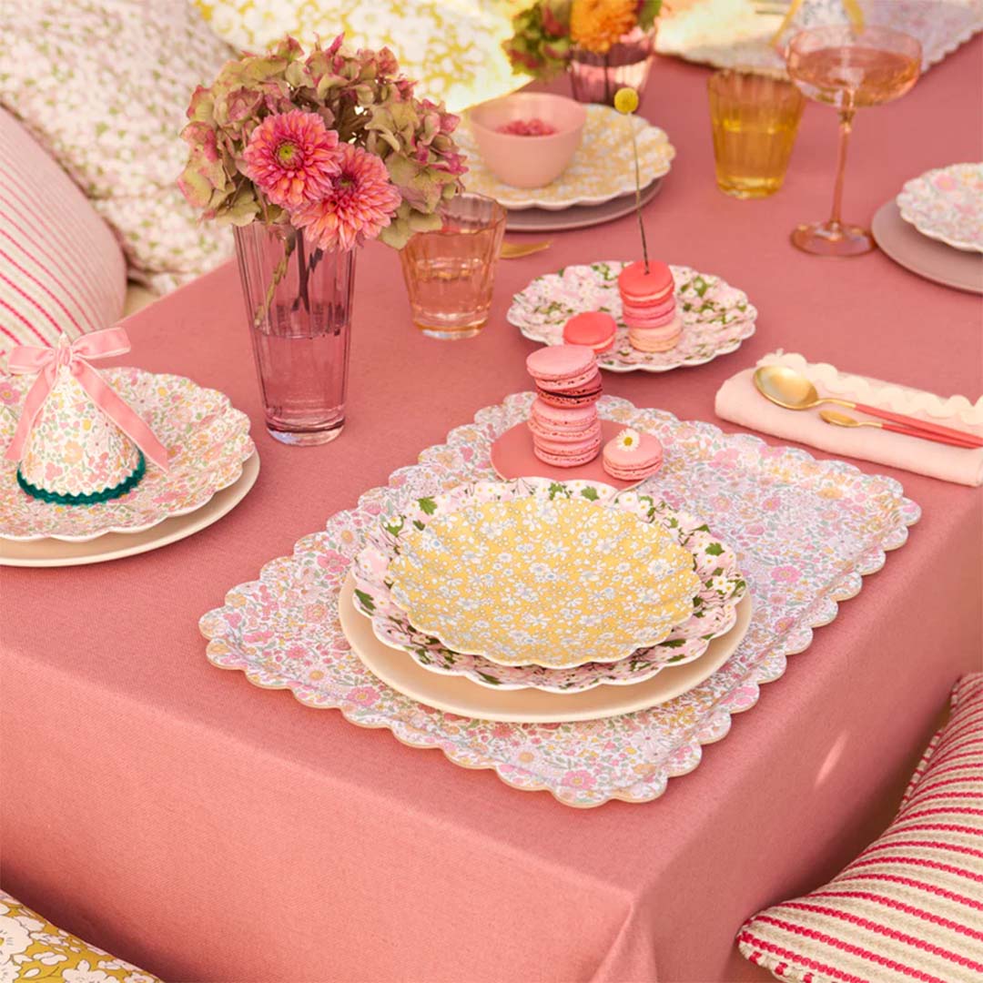 Een feestelijk gedekte tafel met Meri Meri speelgoedborden en placemats met bloemenpatronen.