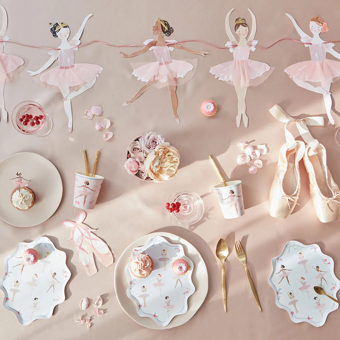 Overzicht van Meri Meri ballerina feestartikelen, waaronder bordjes, bekers en een slinger, op een roze ondergrond.