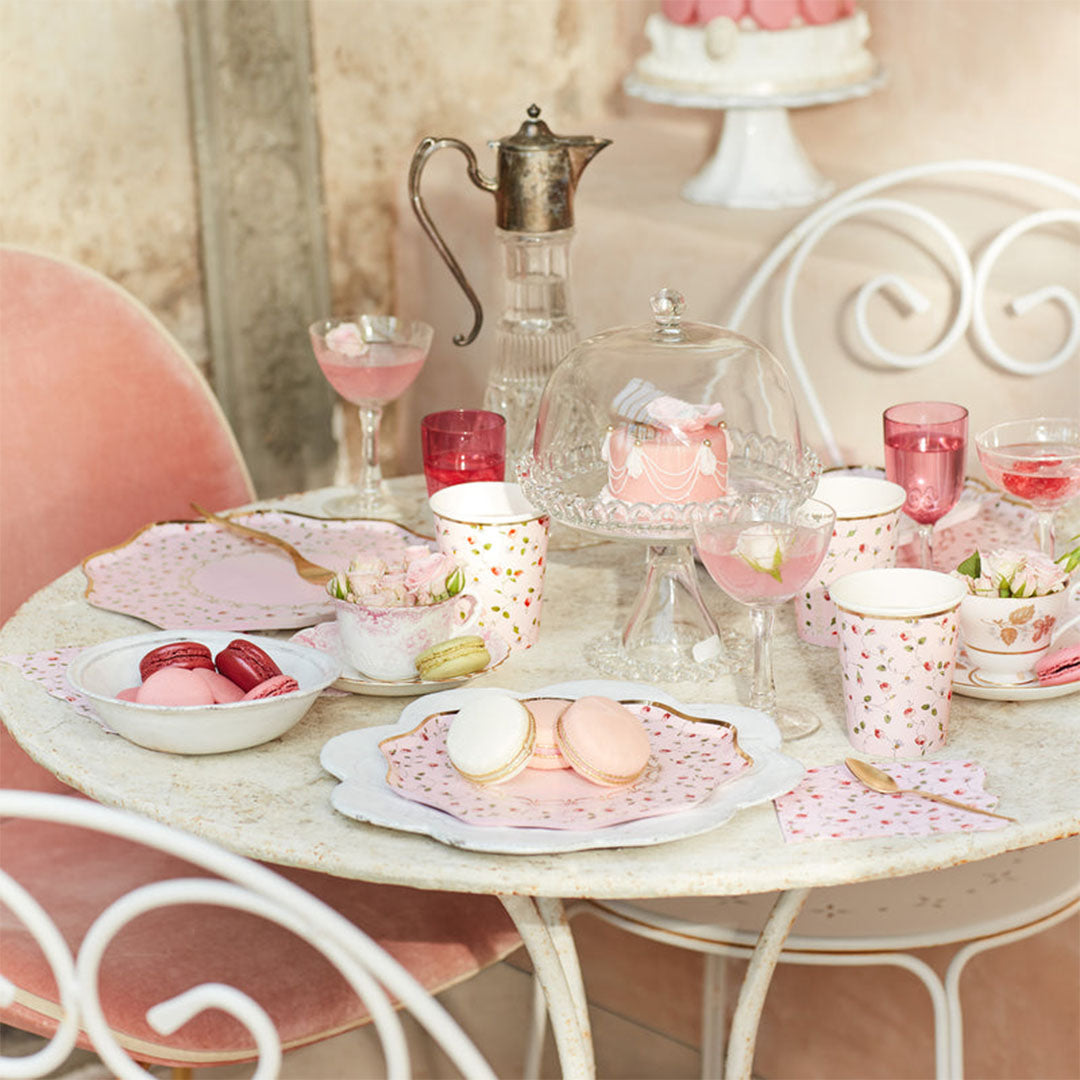 Gedekte tafel met Meri Meri papieren bordjes, kopjes en macarons in een roze feestthema.
