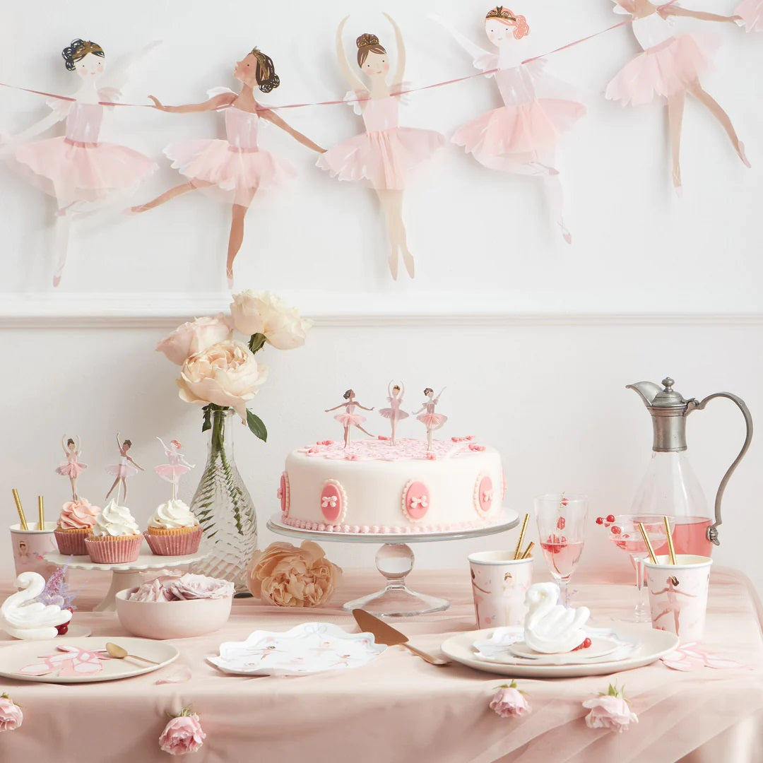 Feestelijk gedekte tafel met Meri Meri ballerina decoraties, inclusief een taart, cupcakes en een slinger.