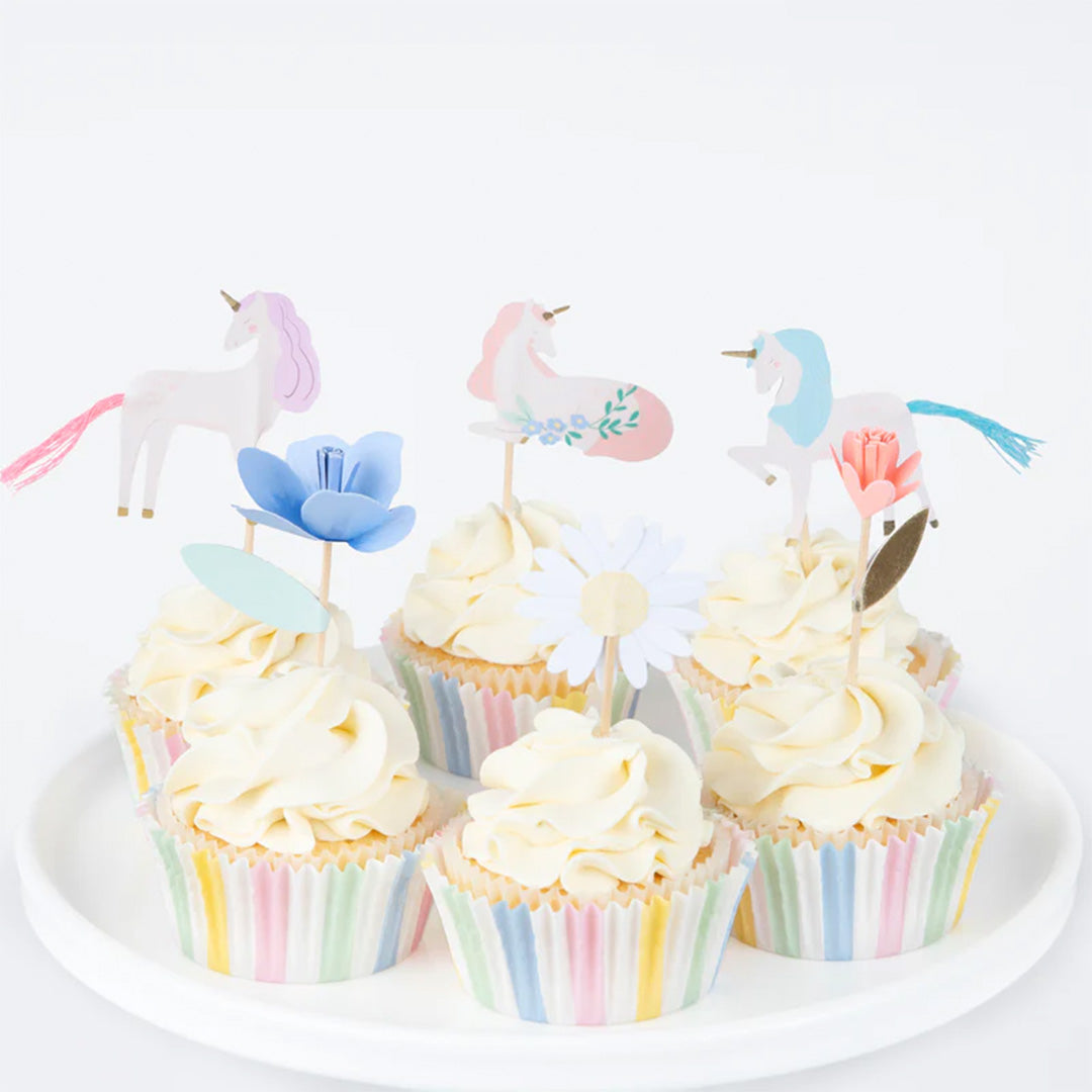 Cupcakes met witte frosting, versierd met Meri Meri eenhoorn en bloem toppers en gestreepte bakvormpjes.
