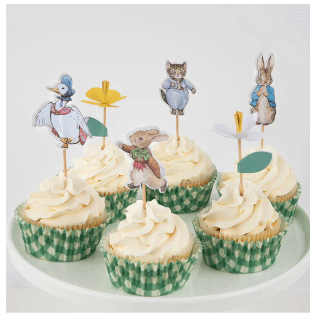 Zes versierde cupcakes met witte frosting, groene geruite vormpjes en verschillende Pieter Konijn karaktertoppers.