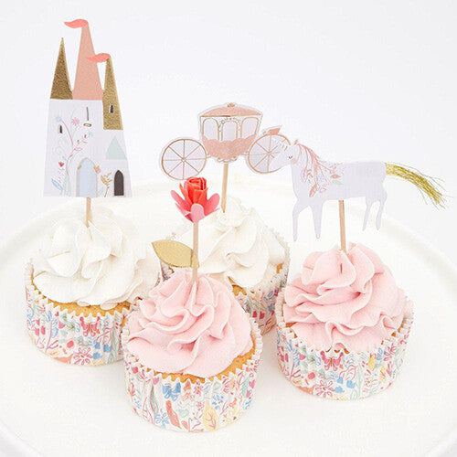 Vier versierde cupcakes met Meri Meri prinsessen toppers van een kasteel, bloem, koets en eenhoorn.