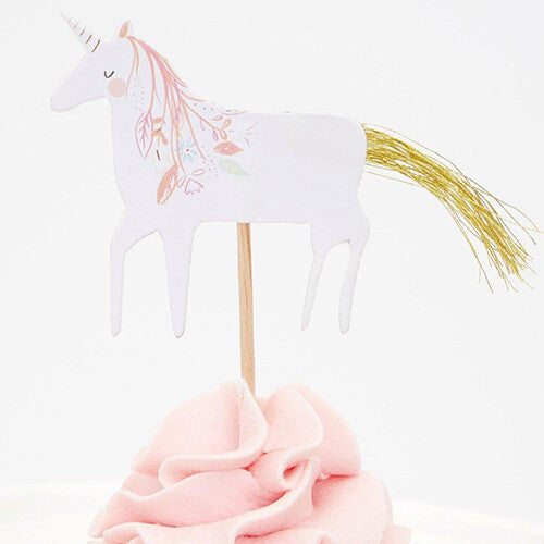 Close-up van een Meri Meri eenhoorn cupcake topper met gouden staart op een roze cupcake.