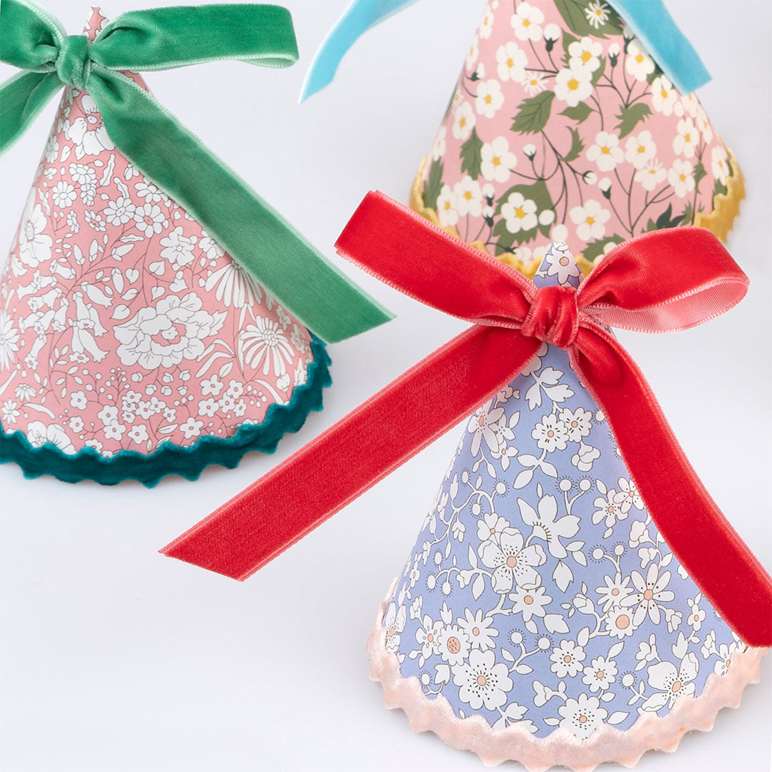 Drie Meri Meri feesthoedjes met gebloemd Liberty patroon en fluwelen strikken, close-up gefotografeerd.