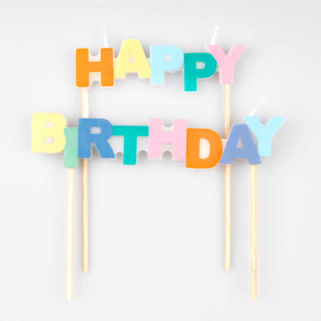 Meri Meri verjaardagskaarsen die de tekst 'Happy Birthday' vormen, frontaal gefotografeerd.