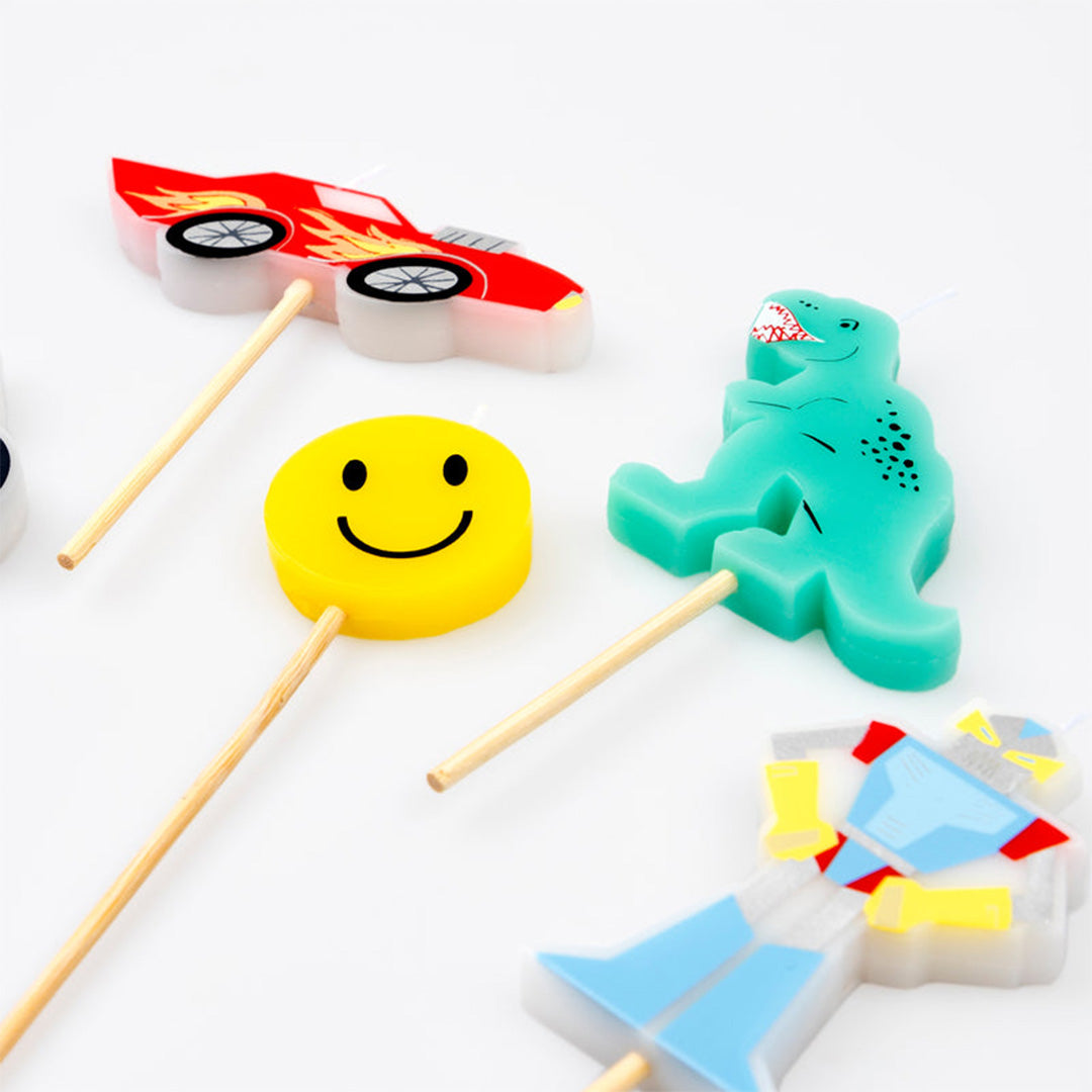 Detailopname van Meri Meri verjaardagskaarsen in de vorm van een raceauto, smiley en dinosaurus.
