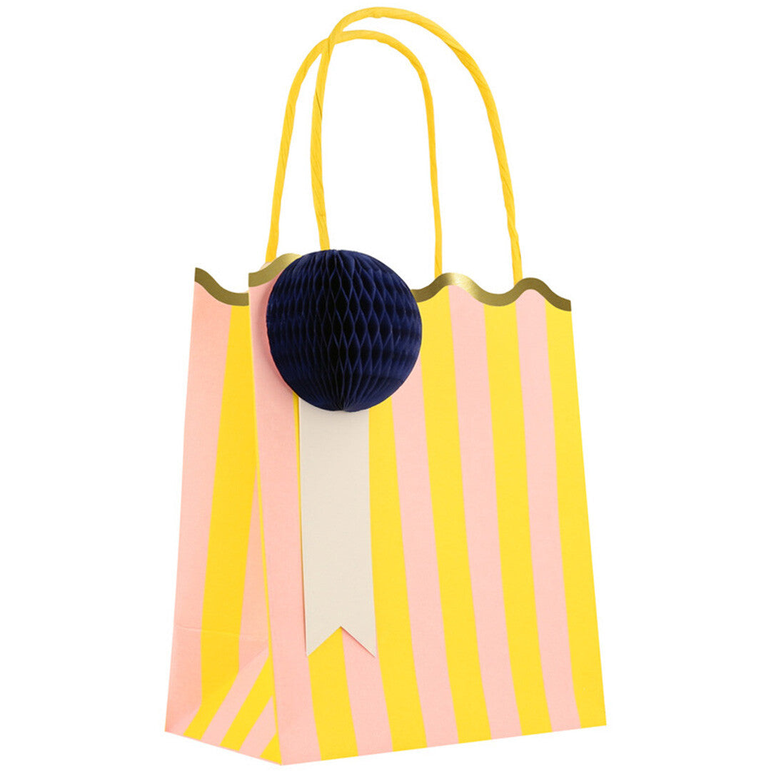 Een Meri Meri gestreept feesttasje in geel en roze met een donkerblauwe honingraatdecoratie.