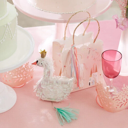 Meri Meri roze papieren cadeautasje met eenhoorn- en kasteelpatroon op een feestelijk gedekte roze tafel met een zwaan decoratie.
