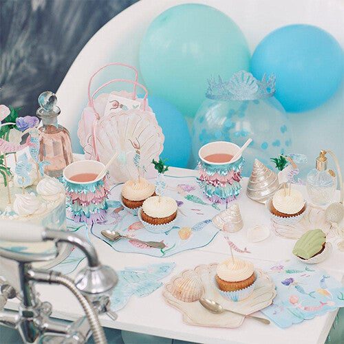 Meri Meri feestartikelen op een feesttafel met zeemeerminthema, inclusief schelpvormige feesttasjes.