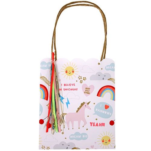 Een wit meri meri feesttasje met een eenhoorn, regenbogen, zonnen en sterren, en kleurrijke kwastjes.