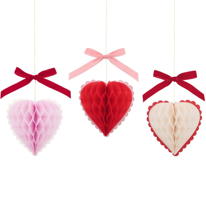 Meri Meri feestversiering van drie hangende honingraat hartjes in roze, rood en crème met strikjes.