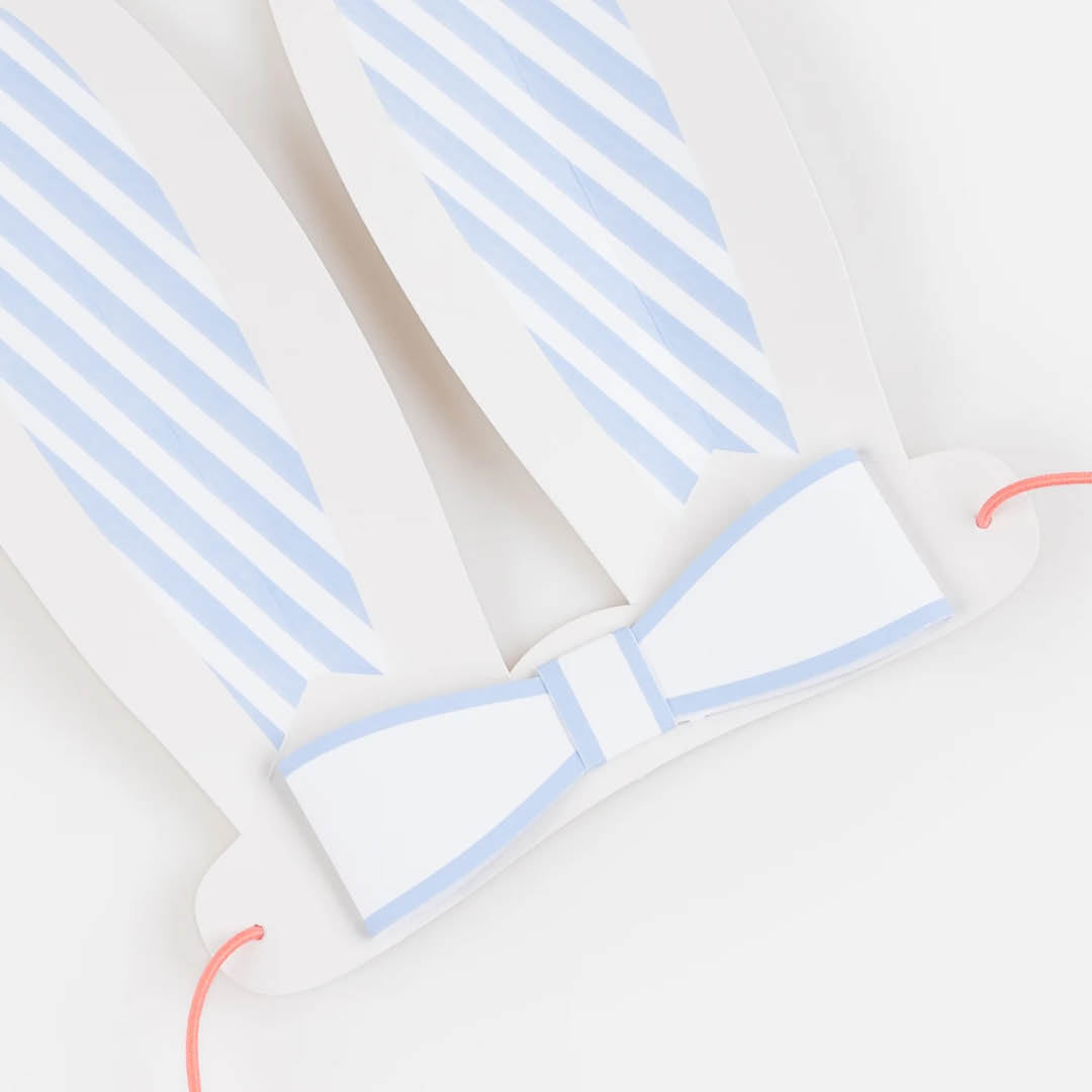 Detail van een blauw-wit gestreept Meri Meri konijnenoor met een lichtblauwe strik en rood elastiek.