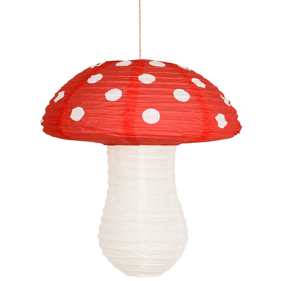 Een grote rode Meri Meri papieren paddenstoel lampion met witte stippen hangt aan een touwtje.