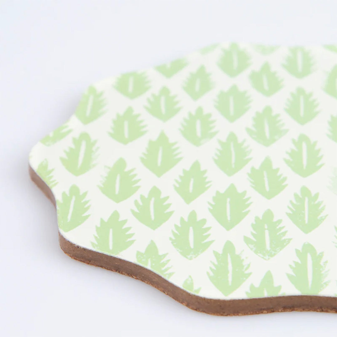 Detail van een onderzetter met een lichtgroen bladpatroon op een witte achtergrond.