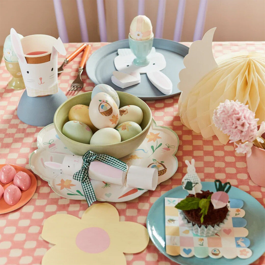 Een gedekte paastafel met versierde eieren, een cupcake en diverse paasdecoraties.