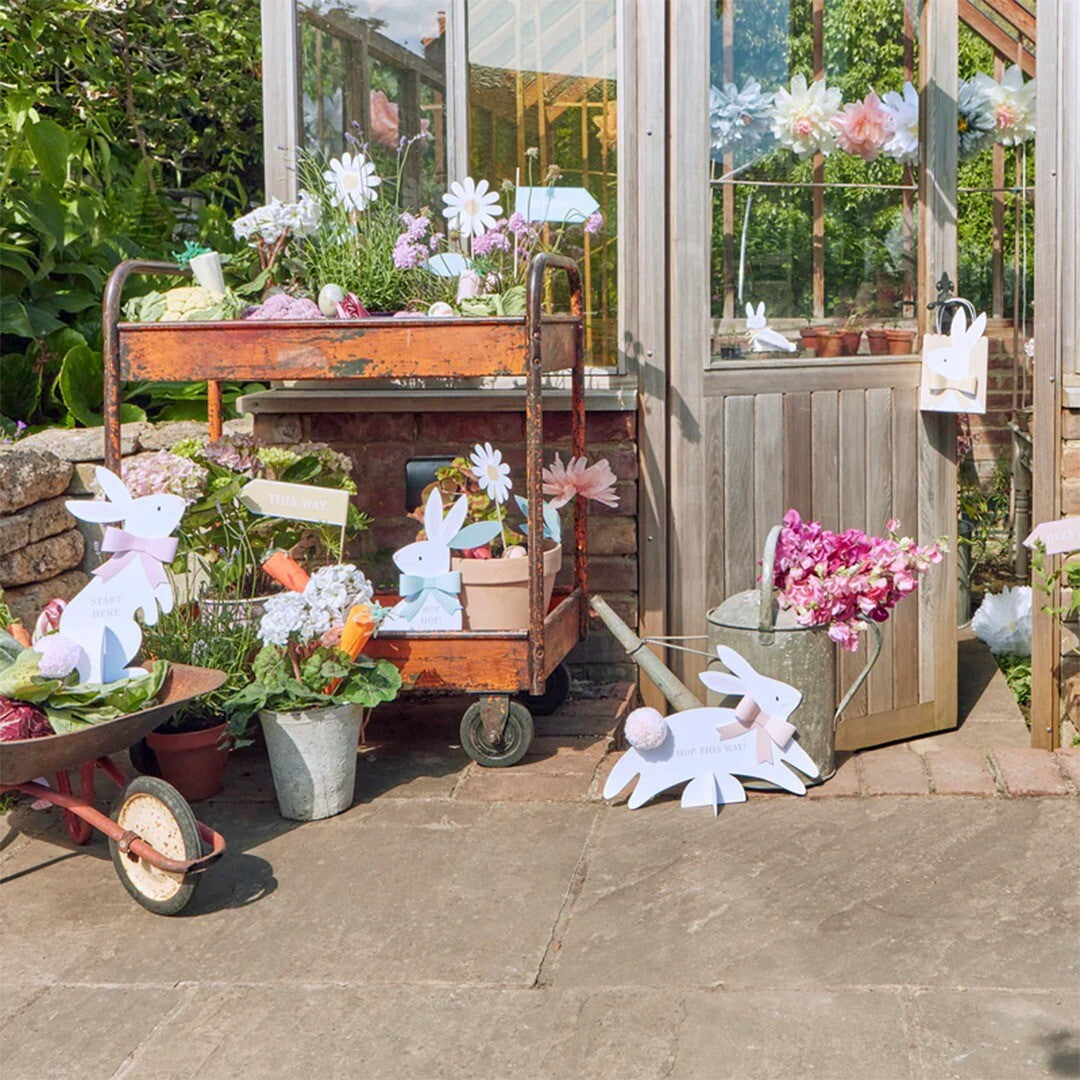 Meri Meri paaseieren wegwijzer set met konijnen en een pijl in een tuin bij een kas.