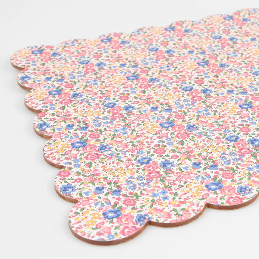 Detail van de Meri Meri placemat met bloemenprint en geschulpte rand, waarbij de kurken zijkant zichtbaar is.
