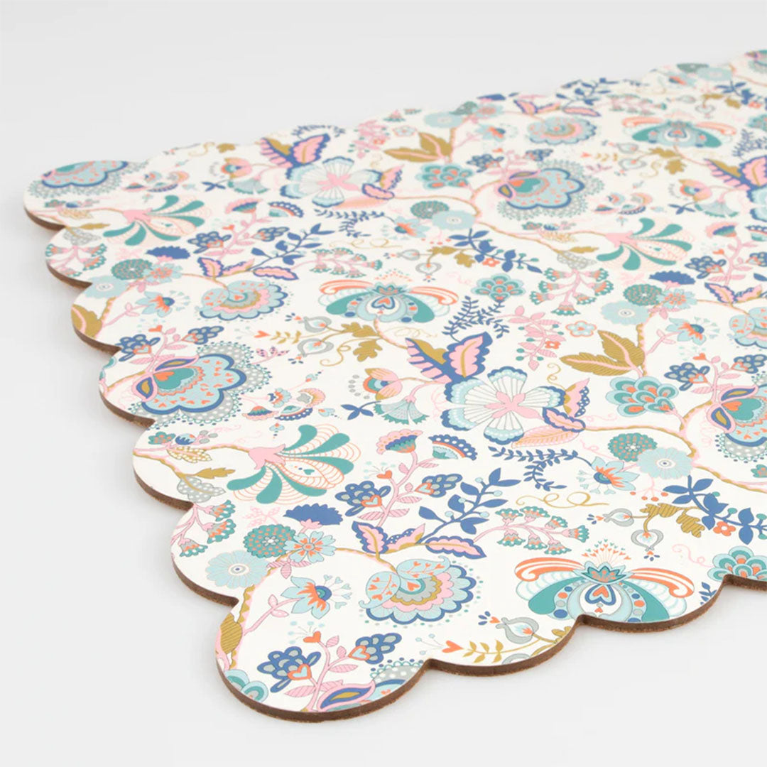 Detail van de Meri Meri placemat met veelkleurig gebloemd patroon en geschulpte rand, schuin van bovenaf gefotografeerd.