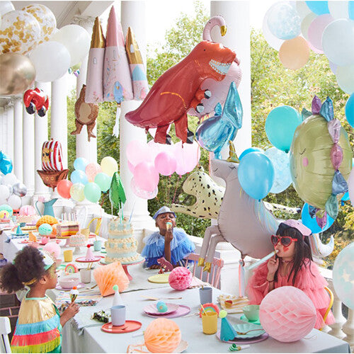 Een feesttafel met kinderen en diverse Meri Meri folieballonnen, waaronder een rode T-Rex, een eenhoorn en een kasteel.