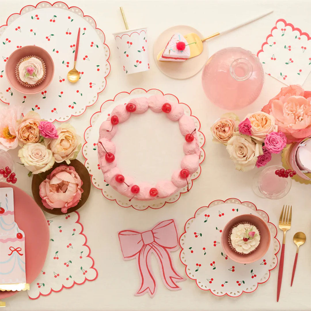 Een feestelijk gedekte tafel met Meri Meri kersen-thema servies en een roze strik servet.